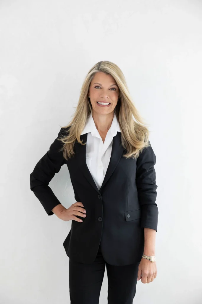 Professional woman in a black blazer and white shirt smiling at the camera